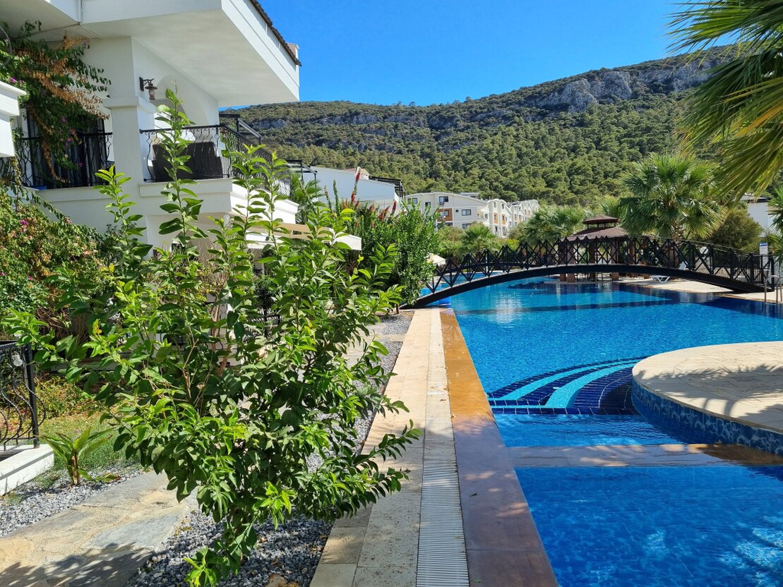 Technician cleaning a swimming pool beside a garden